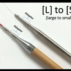 May include: Two knitting needles with adapters. The larger needle is made of metal and has the text "ChicoGeo 10.33 (3.25mm)" printed on it. The smaller needle is made of wood and has the text "ChicoGeo 7.5" printed on it.