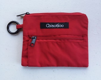 May include: A red zippered pouch with a black zipper and a black ring attached. The pouch has a black label with the text "ChiaoGoo" on it.