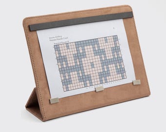 May include: A brown leatherette easel with a gray metal clip holds a sheet of paper with a knitting pattern. The pattern is titled "Savory Knitting Pressed Flowers Cowl Pressed Flowers 8".