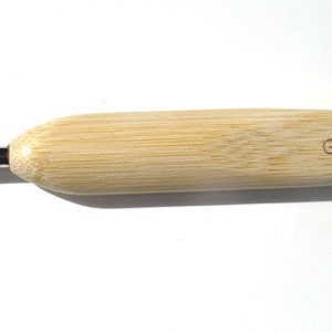 May include: A wooden crochet hook with a silver hook and a wooden handle. The hook is labeled "G/4.00mm".