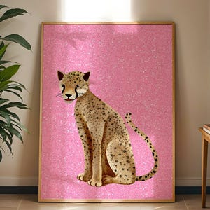 May include: A framed art print featuring a cheetah illustration. The cheetah is depicted with tan fur and black spots, set against a pink glitter background. The artwork is in a wooden frame and is displayed indoors.