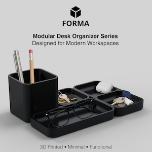 May include: Black modular desk organiser series with a pen holder, trays, and accessories. The organiser includes a pen, pencil, keys, glasses, and other items. The text on the image says "FORMA" and "Modular Desk Organizer Series Designed for Modern Workspaces."
