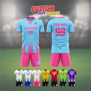 May include: A light blue football kit with pink trim, displaying "TEAMNAME" and the number "99". The image also presents alternative colour schemes, including white, yellow, red, green, and purple. The text "CUSTOM ANY REQUEST" is at the top. The kit is designed for team sports.