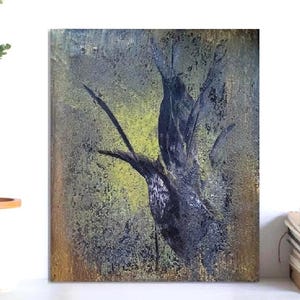 Op de afbeelding: Abstract schilderij van een donkere boom tegen een textuurachtergrond met gele en groene tinten. Het kunstwerk wordt tentoongesteld aan een witte muur, naast een vaas met groen en een stapel boeken met miniatuurhuisjes.
