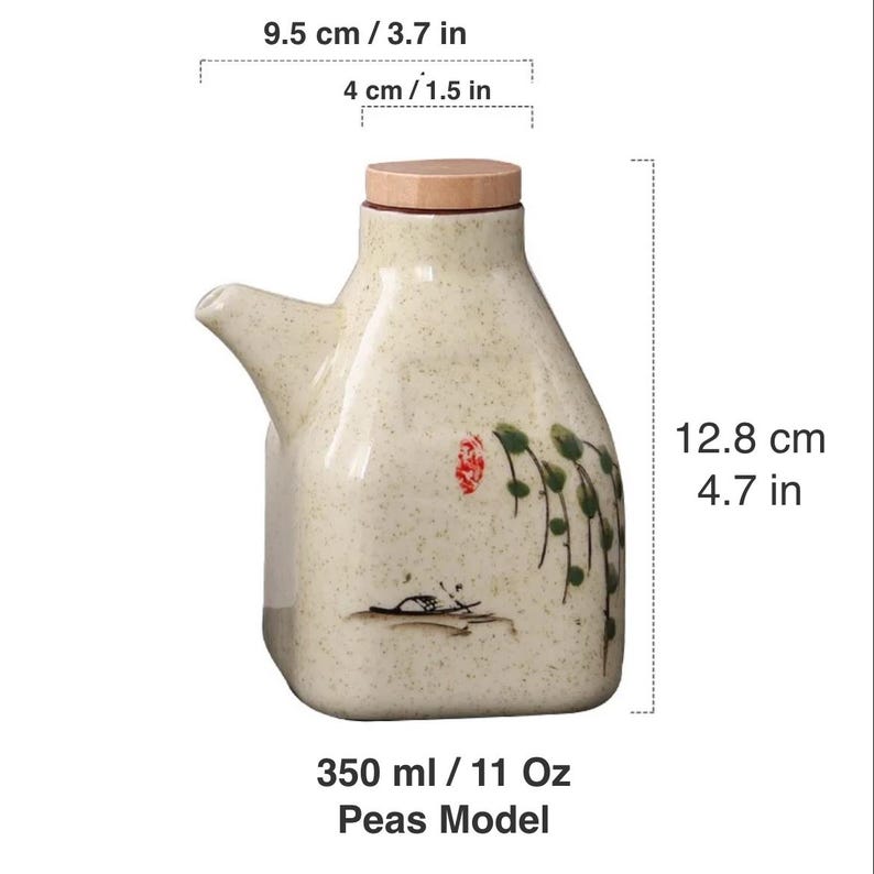 May include: A ceramic oil dispenser with a light beige speckled finish. It features a wooden lid and a spout. The design includes a painted floral and landscape motif. The dispenser is 4.7 inches tall and holds 11 oz.