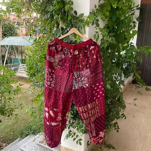 Könnte beinhalten: Eine locker sitzende kastanienbraune Hose mit Patchwork-Design, bestehend aus verschiedenen weißen und hellen Blumen-, geometrischen und Punktmustern. Die Hose hat einen elastischen Bund mit Kordelzug sowie geraffte Beinabschlüsse.