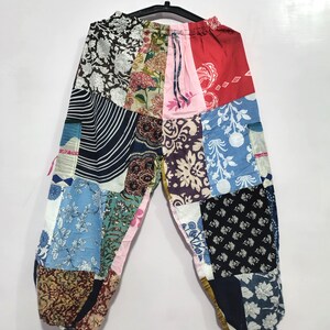 May include: Patchwork trousers featuring a variety of fabric panels in diverse colors and patterns, including floral, striped, and geometric prints. The pants have an elastic waistband with a drawstring and a relaxed, loose-fitting silhouette.