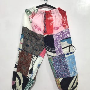 Könnte beinhalten: Patchwork-Hose mit elastischem Bund und Kordelzug. Das Kleidungsstück besteht aus verschiedenen Stoffbahnen in den Farben Rosa, Rot, Weiß, Blau, Violett und Schwarz und zeigt diverse florale, Paisley- und geometrische Muster.