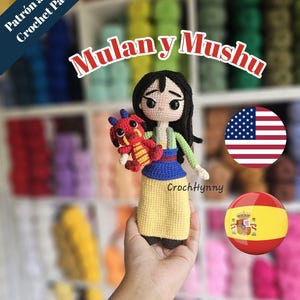 Puede incluir: Muñecas amigurumi de Mulan y Mushu hechas a ganchillo. Mulan lleva una falda amarilla, una blusa azul y pelo negro. Mushu es rojo y amarillo. La imagen incluye el texto "Mulan y Mushu" y "CrochHynny".