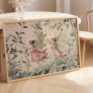 Può includere: Una stampa incorniciata con due fate con abiti rosa e ali verdi, sullo sfondo di un fogliame. L'opera d'arte ha un'estetica vintage, con colori tenui e una cornice in legno chiaro.