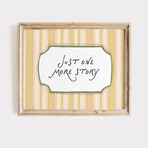 May include: A rectangular wooden frame containing a print with a yellow and white vertical striped background. In the center, a white label with a green border features the black handwritten text that reads, Just one more story.