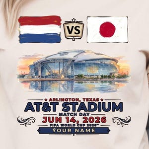May include: Ivory-colored t-shirt featuring the flags of the Netherlands and Japan, with a "VS" graphic. Below, a stadium illustration is printed with the text "AT&T STADIUM" and "JUN 14, 2026". The shirt is a match day design for the FIFA World Cup.