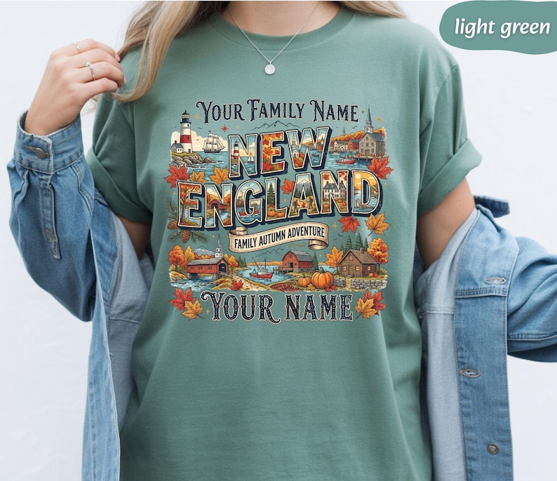May include: A light green t-shirt featuring a graphic print with the text Your Family Name, New England, Family Autumn Adventure, and Your Name. The design includes a lighthouse, a ship, a covered bridge, houses, pumpkins, and autumn leaves.
