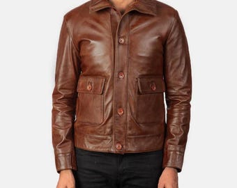 May include: A brown leather jacket with a classic design. The jacket features a collared neckline, button-up front, two chest pockets, and two lower pockets. The jacket has long sleeves and a tailored fit.