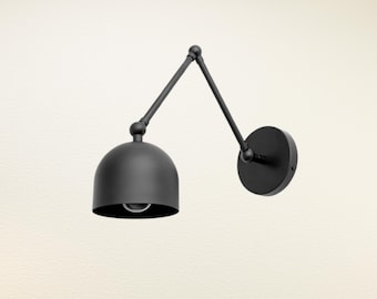 May include: A black, adjustable wall-mounted lamp with a dome-shaped shade. The lamp features a pivoting arm and a circular base, all in a matte black finish. The design is minimalist and modern, suitable for various interior styles.