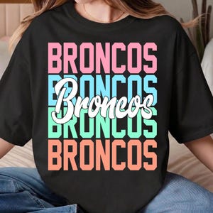 May include: A white ceramic mug with a black handle and the text "But First, Coffee" in a black, bold font. The mug is on a white surface.