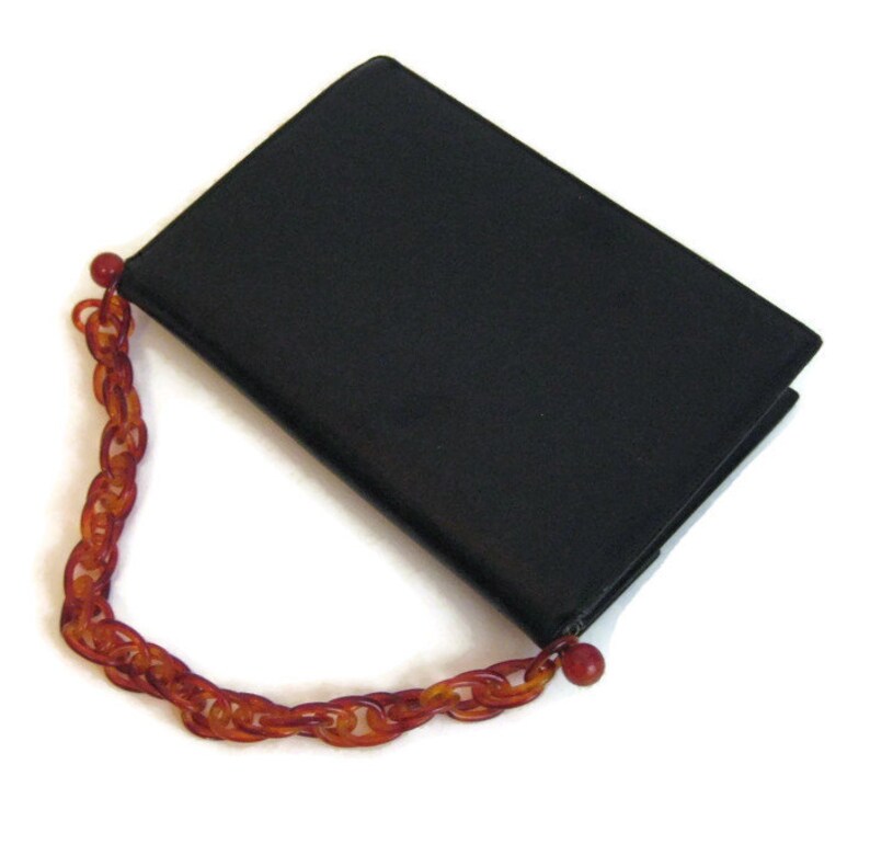 May include: A black leather clutch purse with a brown plastic chain strap.