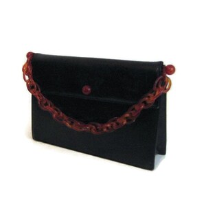 May include: A black leather clutch purse with a red and orange plastic chain strap.