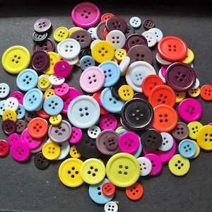 May include: A large collection of colorful buttons in various shapes and sizes. The buttons are made of plastic and have a smooth, glossy finish.