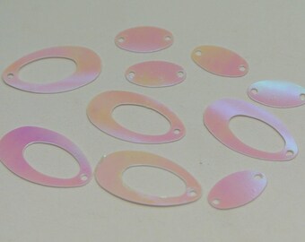 May include: A selection of iridescent sequins in different shapes and sizes. The sequins include oval and teardrop shapes, each with a small hole for sewing. The colours shift from pink to yellow, creating a shimmering effect. These are ideal for embellishments.
