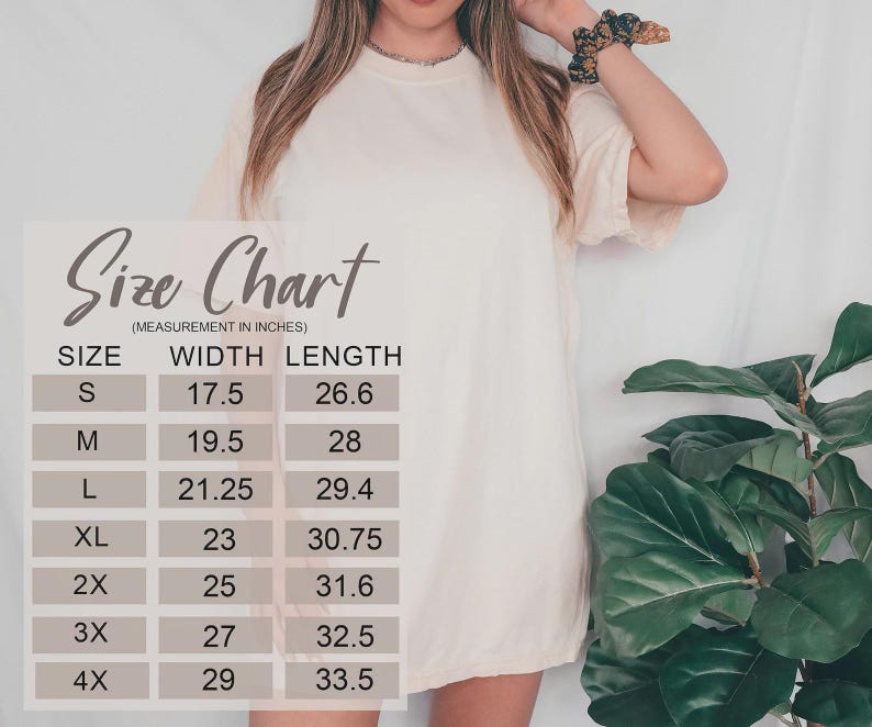 May include: Cream-colored t-shirt with a size chart overlay. The chart lists sizes S through 4X, with width and length measurements in inches. The shirt is worn by a person, with a scrunchie on their wrist.