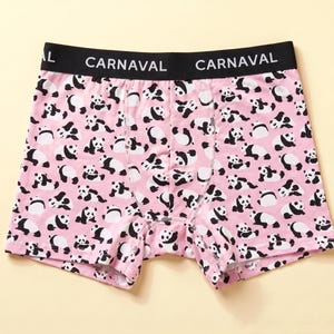 Puede incluir: Calzoncillos tipo bóxer de color rosa con un estampado integral de osos panda en blanco y negro en varias posturas. La prenda tiene una cintura elástica ancha de color negro con la palabra CARNAVAL en letras blancas en el frente.