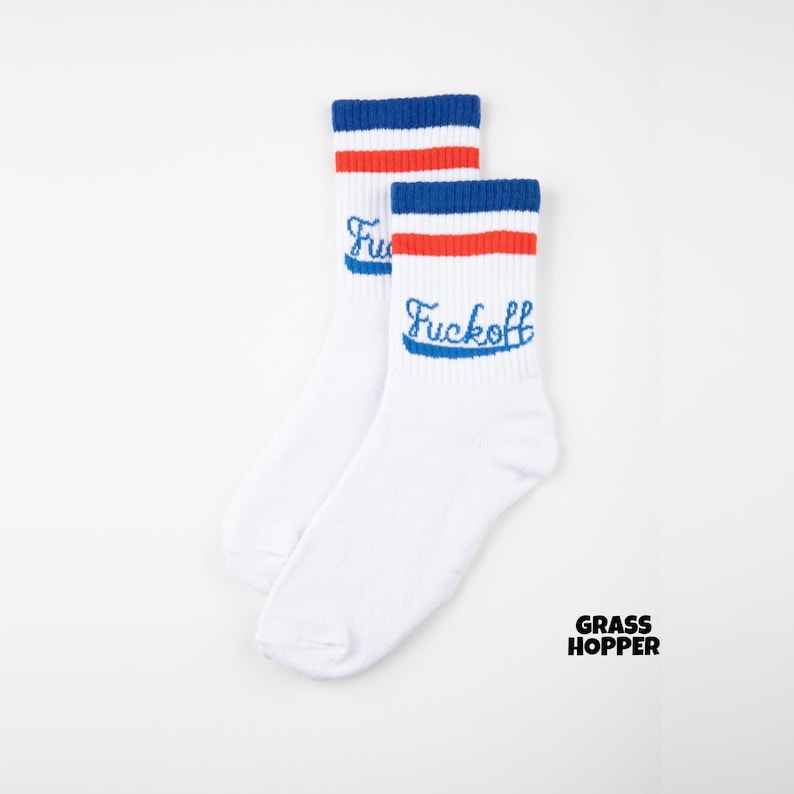 May include: A pair of white socks with blue and red stripes at the top. The word "Fuckoff" is embroidered in blue on the side of each sock. The brand name "GRASS HOPPER" is printed in black on the bottom right.