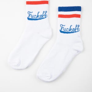 May include: A pair of white socks with blue and red stripes at the top. The word "Fuckoff" is embroidered in blue script on each sock. The socks are displayed on a white background.