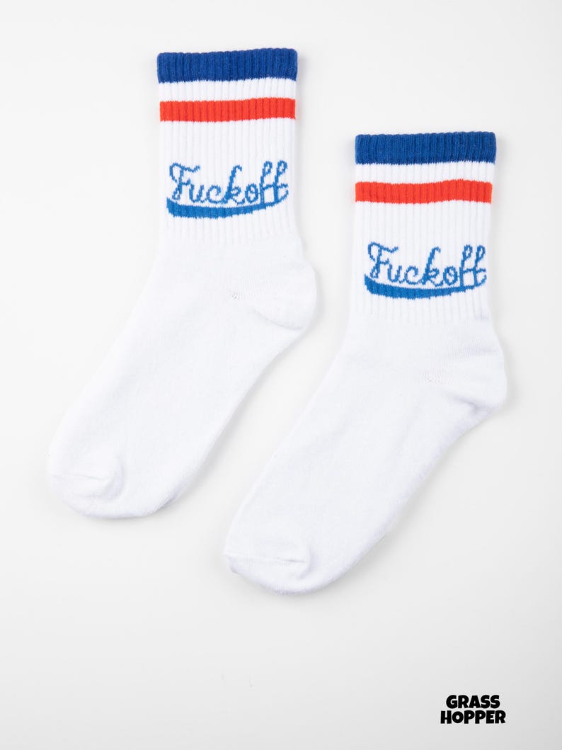 May include: A pair of white socks with blue and red stripes at the top. The word "Fuckoff" is embroidered in blue script on each sock. The socks are displayed on a white background.