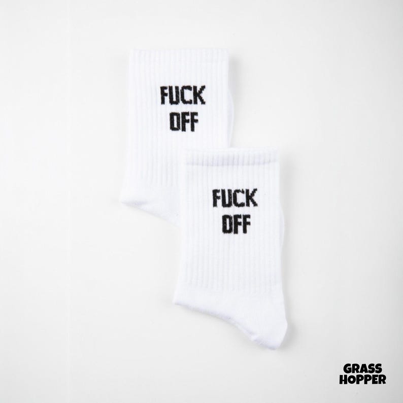 May include: A pair of white ribbed crew socks featuring the text FUCK OFF printed in bold black capital letters on the upper portion of each sock. The design is centered on the front of the fabric, providing a clear and legible display of the text.