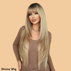 May include: A long, layered blonde wig with dark roots and a full fringe. The wig is styled with long, straight layers and is labeled "Divina Wig" at the bottom of the image. The model is wearing a brown long-sleeved top.