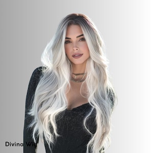Puede incluir: Una mujer con cabello largo y ondulado, rubio platino con raíces oscuras y un ligero tinte rosado. Lleva una blusa negra y un collar plateado en capas. El texto "Divina Wig" es visible en la esquina inferior izquierda.