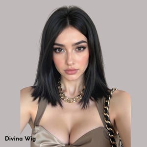 May include: A woman with black hair wearing a gold chain necklace and a brown top. The hair is styled in a shoulder-length bob. The text "Divina Wig" is at the bottom left of the image.