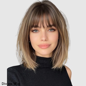 Op de afbeelding: Een vrouw met blauwe ogen draagt een middellange, gelaagde pruik met pony. De pruik heeft een mix van lichtbruine en blonde tinten. De vrouw draagt een zwarte coltrui. De tekst "Divina Wig" is linksonder zichtbaar.