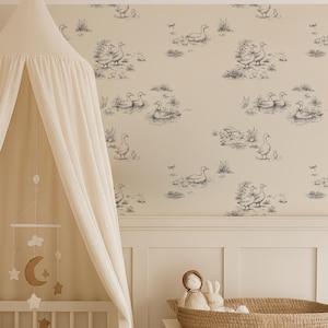 May include: A nursery scene with a white crib, canopy, and dresser. The crib is adorned with a cable-knit blanket, pillows, and stuffed animals. The wallpaper features a blue and white goose pattern. A mobile with stars and a moon hangs above the crib.