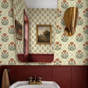 Può includere: Interno bagno con lavabo bianco a colonna, rubinetteria in ottone, grande specchio con cornice dorata e applique a parete. Le pareti sono decorate con carta da parati floreale nei toni dell'arancio, verde e crema, completata da boiserie rosso scuro.