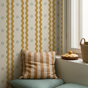 May include: A cozy corner with a striped pillow and a teal cushion on a wooden bench. The background features a cream-colored wallpaper with mustard yellow wavy stripes and small blue floral accents. A window with a basket and a wooden plate with fruit is visible.