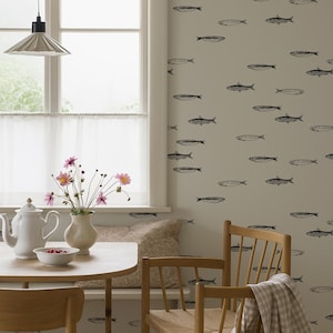 K&ouml;nnte beinhalten: Ein Esszimmer mit einem runden Holztisch, zwei Holzst&uuml;hlen und einer Bank. Die Wand ist mit einem Fischmuster verziert. Eine wei&szlig;e Teekanne, eine Sch&uuml;ssel mit Beeren und eine Vase mit Blumen stehen auf dem Tisch. Ein kariertes Tuch h&auml;ngt &uuml;ber einem Stuhl.