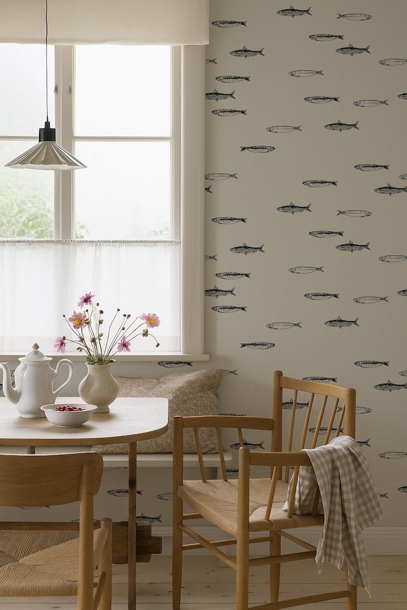 K&ouml;nnte beinhalten: Ein Esszimmer mit einem runden Holztisch, zwei Holzst&uuml;hlen und einer Bank. Die Wand ist mit einem Fischmuster verziert. Eine wei&szlig;e Teekanne, eine Sch&uuml;ssel mit Beeren und eine Vase mit Blumen stehen auf dem Tisch. Ein kariertes Tuch h&auml;ngt &uuml;ber einem Stuhl.