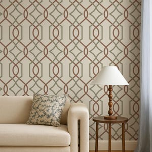 Puede incluir: Un sofá beige con un cojín estampado se encuentra frente a una pared con un diseño geométrico en tonos marrón y gris. Una mesa auxiliar de madera con una lámpara está al lado del sofá.