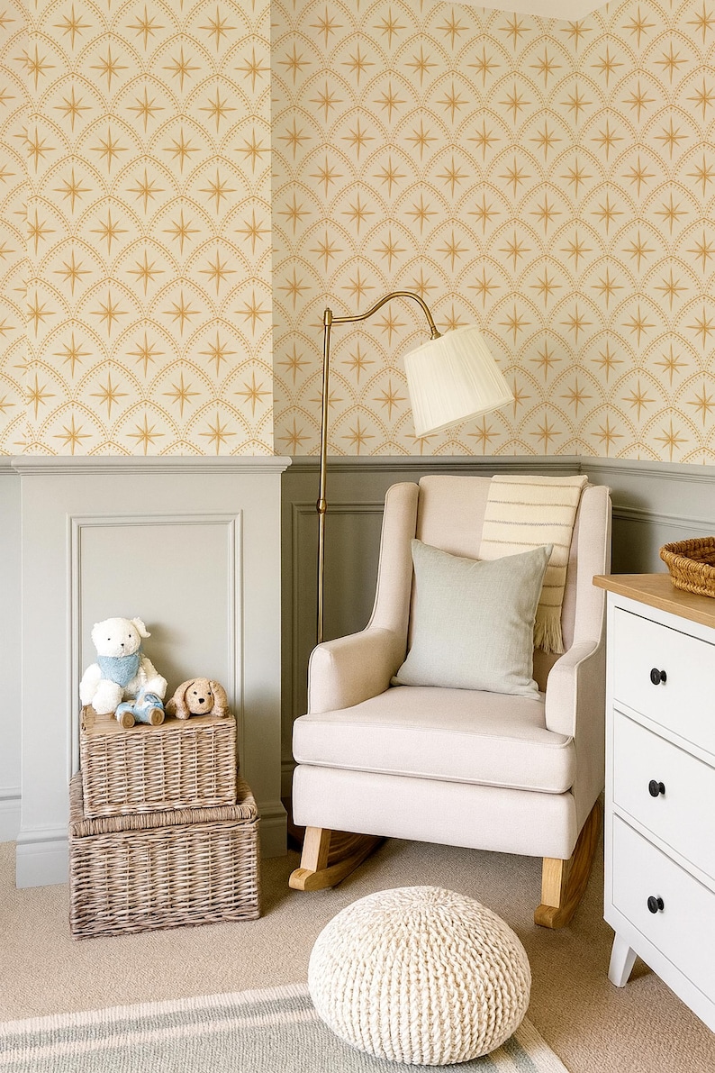 May include: A beige upholstered rocking chair with a light green throw pillow and a striped blanket, positioned near a brass floor lamp, two stacked wicker storage baskets with plush toys, a white dresser, and a cream-colored knit pouf.