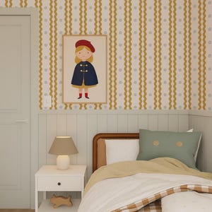 May include: A child's bedroom with a framed illustration of a girl in a red beret and blue cape. The room features a bed with a checkered comforter, a white nightstand with a lamp, and yellow and white striped wallpaper.