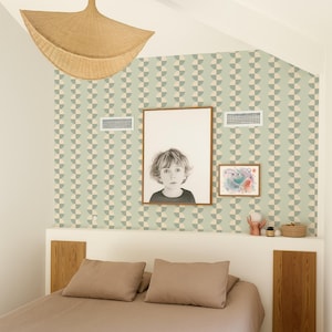 May include: Bedroom interior with a bed, pillows, and a neutral-toned duvet. The wall features a geometric pattern wallpaper and framed artwork. A woven pendant light hangs from the ceiling, and a small shelf displays decorative items.