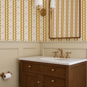 May include: A bathroom interior featuring a dark wood vanity with a white marble countertop and gold fixtures. The walls are decorated with a cream-colored wallpaper with yellow wavy stripes and small gray floral accents. A gold-framed mirror and sconces complete the space.