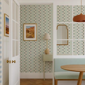 May include: Interior scene with a light blue and beige geometric patterned wallpaper. A white door with gold hardware opens to reveal a room with a small table, bench, and a round wooden table. A framed landscape art piece hangs on the wall.