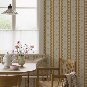 May include: A cozy dining area with a round wooden table, two wooden chairs, and a bench. A white teapot, bowl of berries, and vase of flowers sit on the table. The walls have a yellow and white wavy pattern.