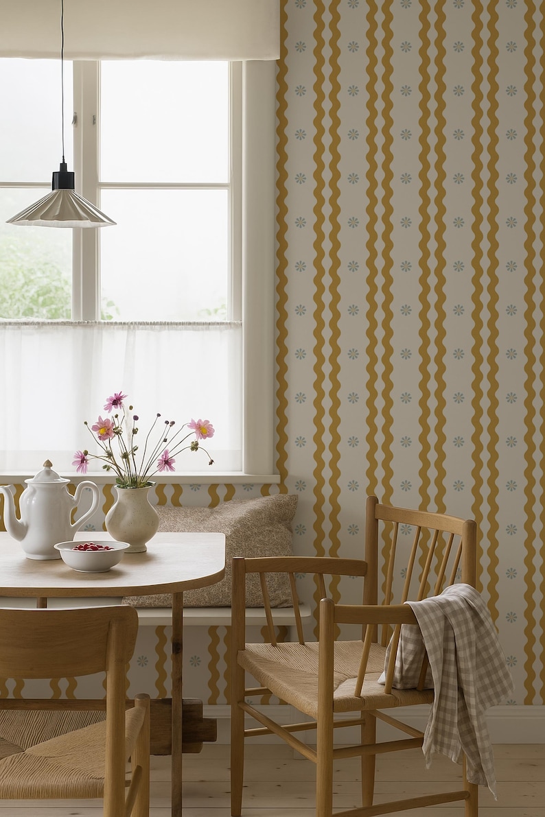 May include: A cozy dining area with a round wooden table, two wooden chairs, and a bench. A white teapot, bowl of berries, and vase of flowers sit on the table. The walls have a yellow and white wavy pattern.