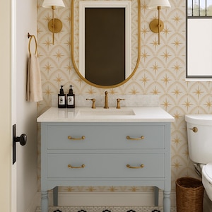 May include: A bathroom vanity with a light blue finish, two drawers, and brass hardware, topped with a white countertop, a sink, and a brass faucet. Above the vanity is an oval mirror with a brass frame, flanked by two wall-mounted lamps.