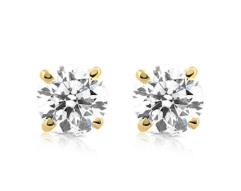 Può includere: Un paio di orecchini a lobo con diamanti rotondi e trasparenti con castoni in oro. I diamanti brillano su uno sfondo bianco. Questi orecchini classici sono un elemento base della gioielleria senza tempo.