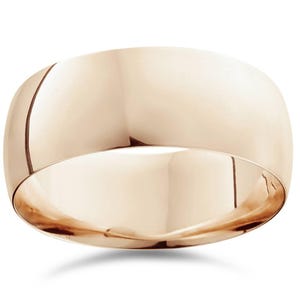 Op de afbeelding: Een gepolijste, roségouden ring met een afgerond, gewelfd ontwerp. De ring heeft een glad, reflecterend oppervlak en het licht reflecteert van de gebogen vorm. De ring is een eenvoudige band, zonder zichtbare versieringen.